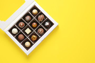 Box with delicious chocolate candies on color background