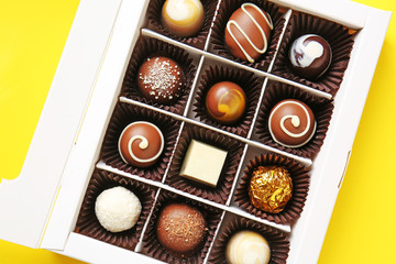 Box with delicious chocolate candies on color background