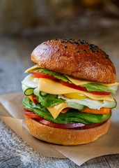 Appetizing vegetarian burger with vegetables, cheese and quail eggs.  Whole grain bun without yeast.  The concept of a plant-based diet and a healthy diet.  Close-up.
