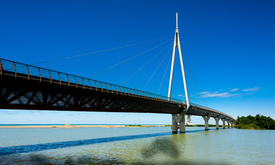 A modern bridge connecting two islands with pastel blue skies