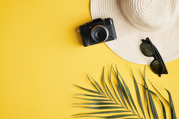 Flat lay traveler accessories on yellow background. Top view female beach hat, vintage camera,...