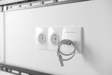Electric outlets and network socket with coiled Ethernet cable inside black metal frame for...
