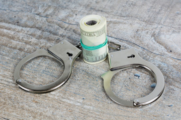 Handcuffs and usa dollar banknotes on wooden background