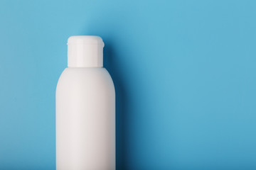 White bottle of cream on a blue background with space for text. Free space for text.