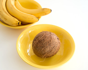 Whole coconut and bananas in a yellow plate