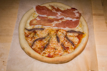 Pizza artigianale fatta in casa al forno con rucola acciughe salsiccia mozzarella pomodoro