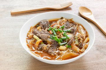 close up of stir fried beef with kimchi in a ceramic bowl on wooden table. asian homemade style food concept.