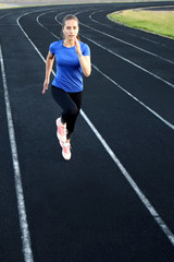 Fototapeta premium Runner athlete running on athletic track training her cardio in stadium. Jogging at fast pace for competition