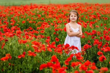 Obraz na płótnie Canvas Cute child girl in poppy field