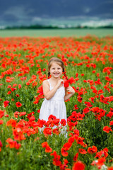 Naklejka na ściany i meble Cute child girl in poppy field