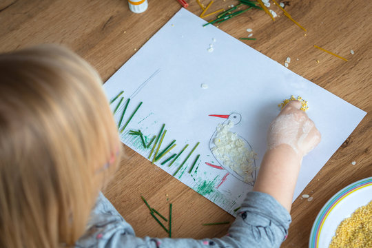Preschooler paints pictures at home using pasta and couscous