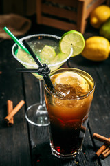 Two cocktails margarita and long island on the wooden background, vertical