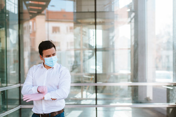
Young businessman with gloves and face mask in front of company. COVID - 19 virus protection