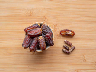 dates in a bowl on a wooden table . Top view.