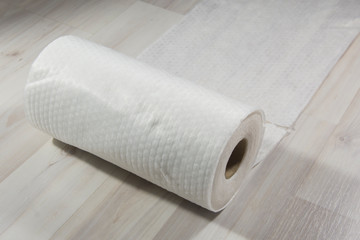 A roll of kitchen towel lies on a light table. Kitchen rag
