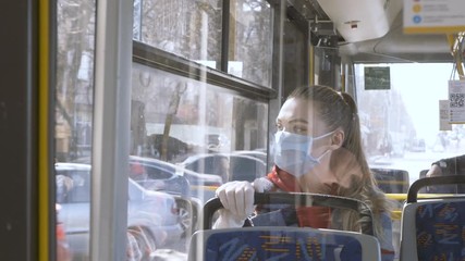 Adaptation to life in self-isolation COVID 19. A woman in a medical mask rides on a public bus, transport.