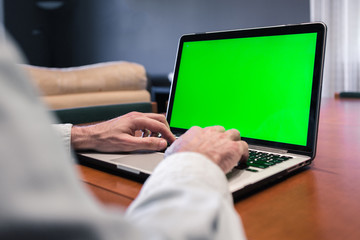 Man working at home on a computer with mock-up green screen. Quarantine and covid19 concept