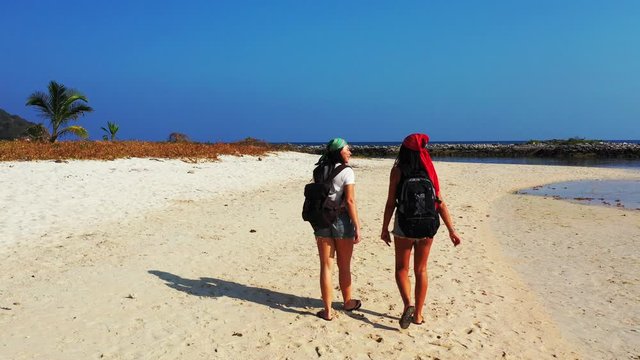 Two friends girls wearing in modern style walking on white sandy beach and watching beautiful seascape in Cambodia