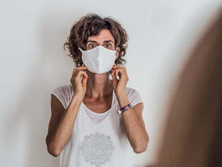 woman protecting from corona virus covid-19 putting on a white medical face mask on neutral...