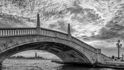 A typical bridge, Ponte San Biasio delle Catene, in the historic center of Venice, Italy, under which you can see the island of San Giorgio Maggiore, in black and white