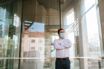 
Young businessman with gloves and face mask in front of company. COVID - 19 virus protection