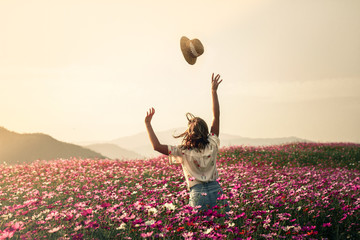 A girl throws her har in a field of colourful flowers.