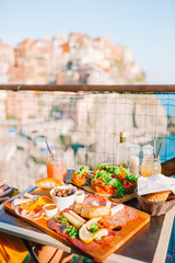 Fresh bruschettes, cheeses and meat on the board in outdoor cafe with amazing view in Manarola