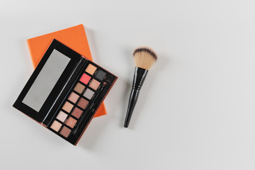 Makeup artist's notebook with palette and blush brush on white background. Copy space, top view.