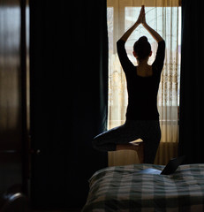 woman in a yoga pose in bedroom staying fit and mentally healthy at home