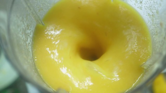 Making fresh mango fruit shake in blender. The concept of a healthy lifestyle. Close up, slow motion, top view