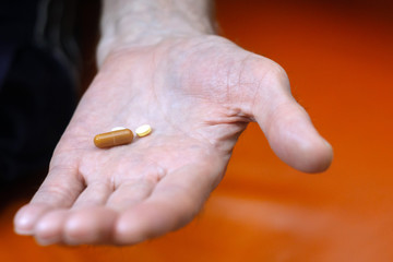 pills in hand close up selective focus in an old mans hand