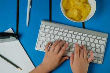 Young boy is sitting at the computer doing homework, playing a game, watching videos and eating chips.