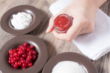 A woman holds a jar of natural homemade scrub. Skin care. Natural ingredients for making a scrub, sugar, cream, berries. Moisturizing, exfoliating, peeling. Home Cosmetics, Spa Treatment, eco, vegan
