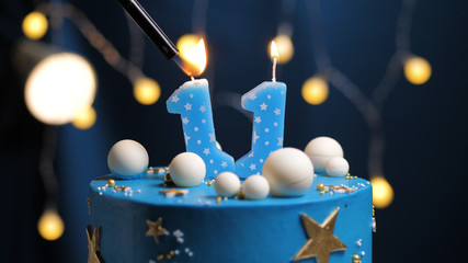 Birthday cake number 11 stars sky and moon concept, blue candle is fire by lighter. Copy space on...