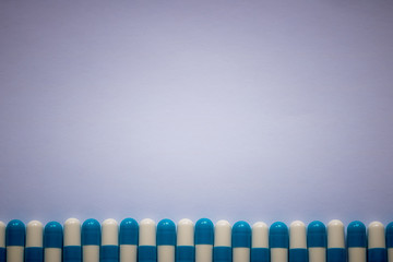 blue-white pills lined up against a plain background