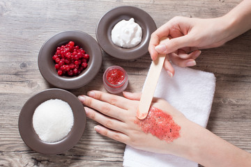 A woman applies a natural homemade scrub with a spatula. Skin care. Natural ingredients for making a scrub, sugar, cream, berry. Moisturizing, exfoliating, peeling. Home Cosmetics, Spa Treatment, Eco