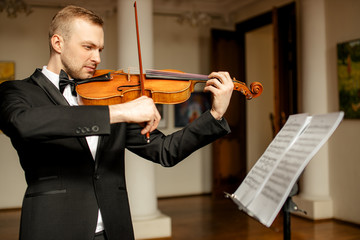 young caucasian violinist perform classical music in music conservatory, man practicing performance, use notes