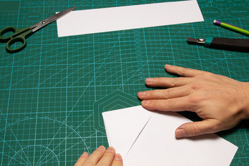 Origami project on white paper with cutter and scissors