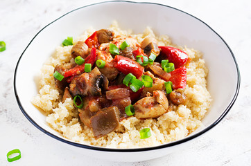 Bulgur and sauteed chicken, mushrooms, eggplants, paprika and tomatoes in a white bowl.