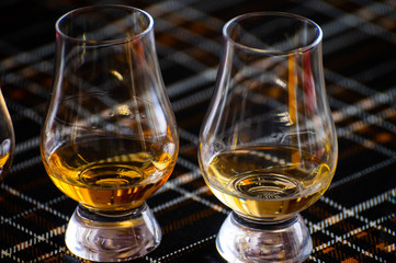 Special tulip-shaped glasses for tasting of Scotch whisky on distillery in Scotland, UK and dark tartan