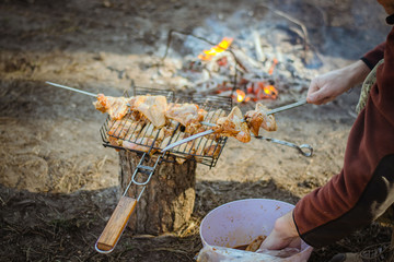 Warmth, love, romance. Spring break. Picnic. Kebab. B-B-Q. Chicken on the grill near the fire. Bonfire in the forest. Chicken chunks skewers, grill, barbecue. On a metal bbq. In the grilling stages.