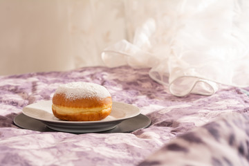 Morning breakfast. Sweet sugar doughnut under the sun on the bed of purple tones. Horizontal position