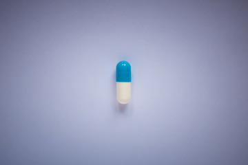 one blue-white pill on a plain background