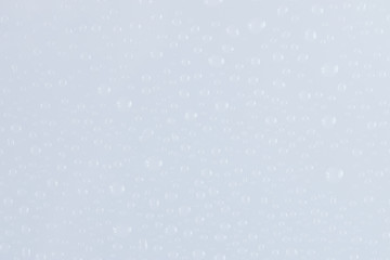 Water drops on glossy blue glass surface texture abstract background