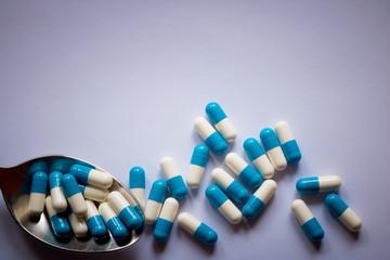 blue and white pills on a spoon