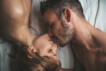 Sensual and romantic young couple kissing and making love on the bed at home. Love concept