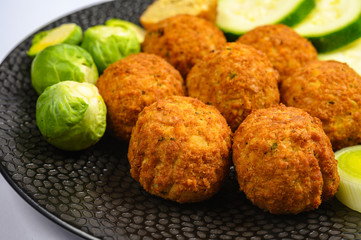 Cooking of healthy vegetarian food, tasty check pea falafels and frehs green vegetables