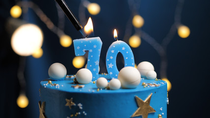 Birthday cake number 70 stars sky and moon concept, blue candle is fire by lighter. Copy space on...