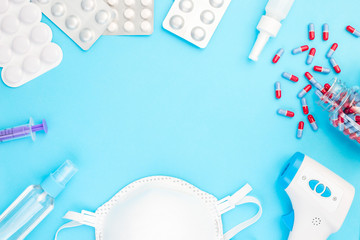 Different medicine on the table, mask, infrared body thermometer, sanitizer,  pills, nose spray,...