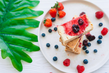 Slice of classic cheesecake with fresh berries on the white plate - healthy organic summer dessert.